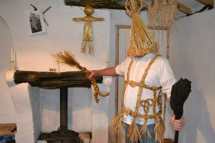 Man in straw outfit holding a Cailleach doll, another can be seen in the background